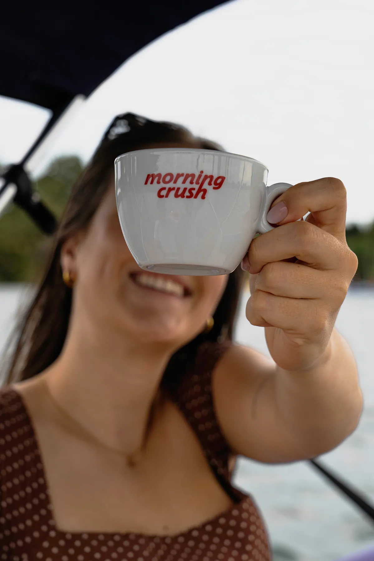 A Morning Crush cup held up to the camera on the boat